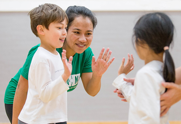 Two children with autism give each other a high five with the support of a volunteer in our I CAN Be Active program.