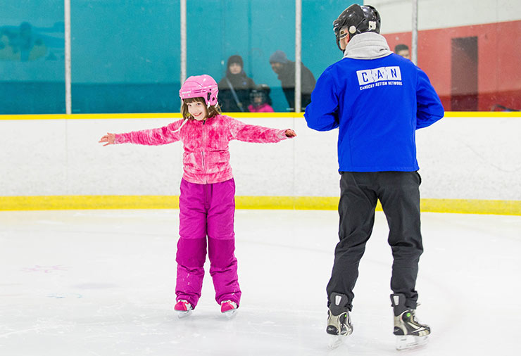 A child with autism ice skates under the watch of a support worker in our I CAN Skate program.