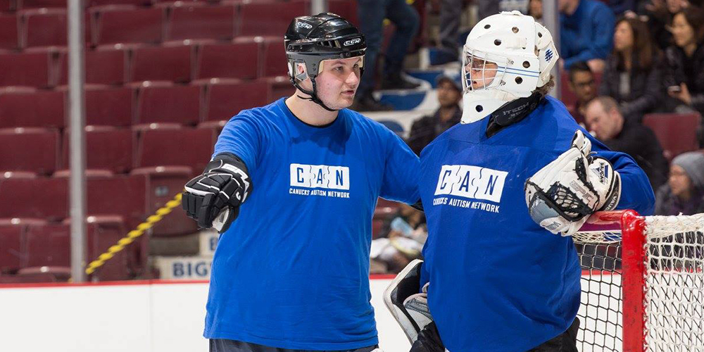 A male coach talking with an ice hockey goalie on the ice.
