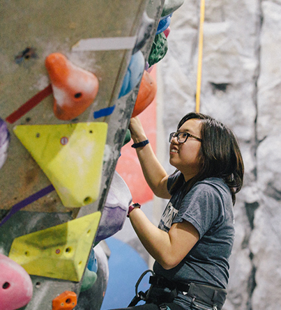 A young adult woman rock climbing