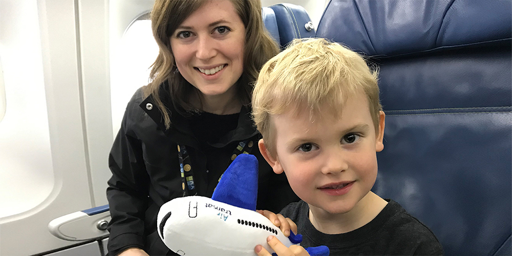 A mother and son pose for a photo on an airplane during the 2019 CAN & YVR Autism Accessibility Tour.